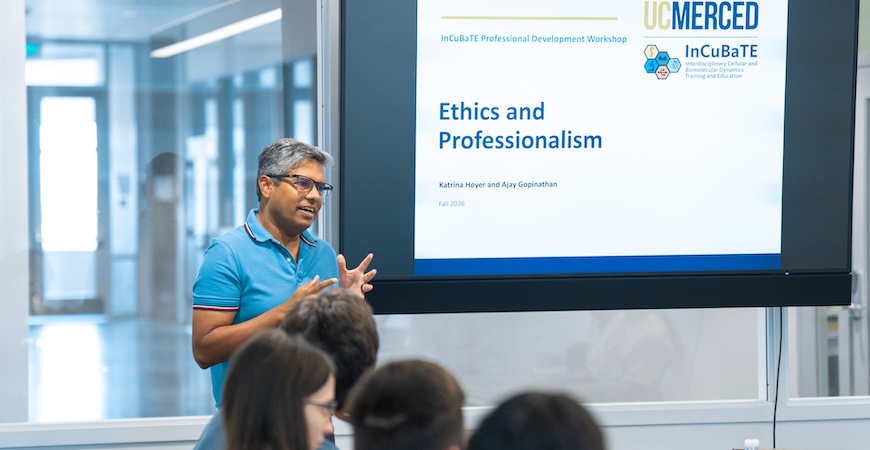 Professor Ajay Gopinathan speaks to students in front of a screen reading 
