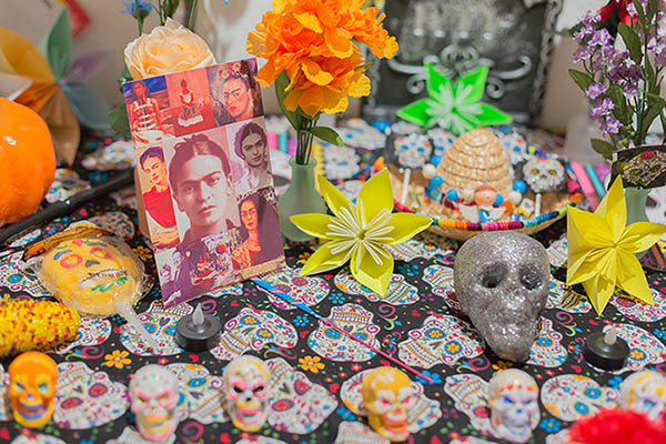 A close up of an altar showcases traditional themes associated with Dia de los Muertos, like skulls and flowers.